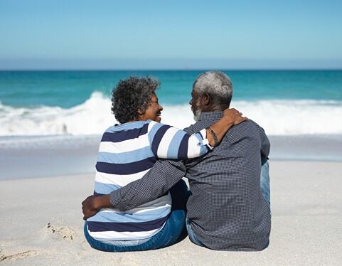 A retired couple sitting on the beach