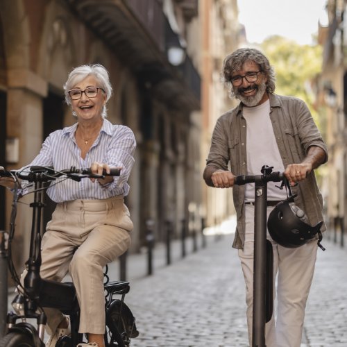 A retired couple riding scooters through a city