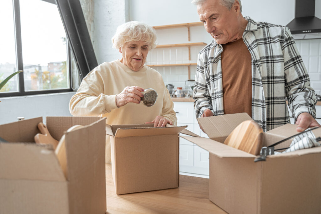 An older couple unpacking boxes in the kitchen of their new home after moving with a lifetime mortgage.